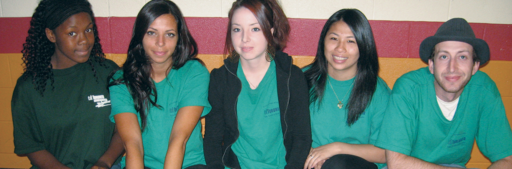 Volunteers sitting against the wall, smiling