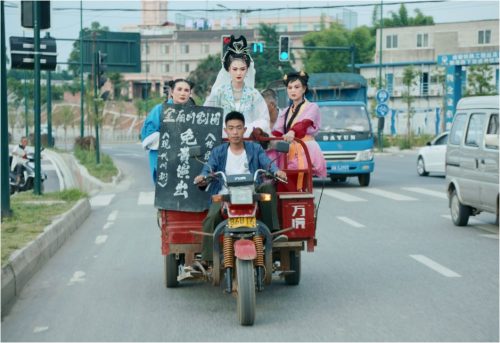 Image info: To Live to Sing,@ImageXProductions. 4 people riding auto rickshaw. 3 people in full opera costume.
