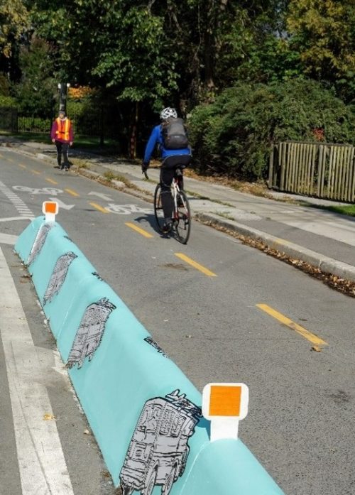 Photo showing concrete jersey barrier next to cyclist riding in bike lane