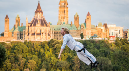 Creations in Vivo artist performing on high sway poles with a view of Ottawa Parliament in the background.