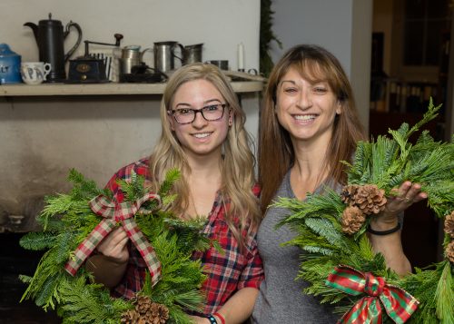 Two guests show off holiday wreaths