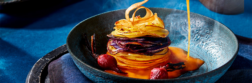 Image of bowl of stacked vegetables with soup being poured from above.