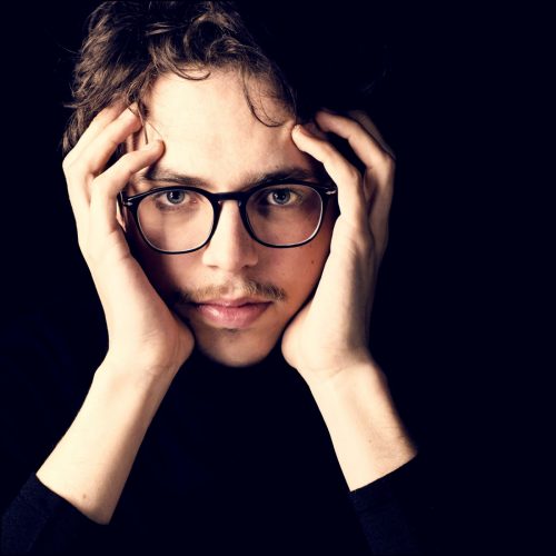 Lucas Debargue starring at camera - closeup of face and hands