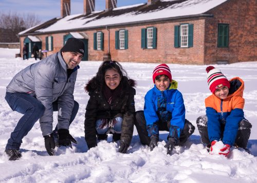 A family of 4 at Fort York in the winter snow and sun.