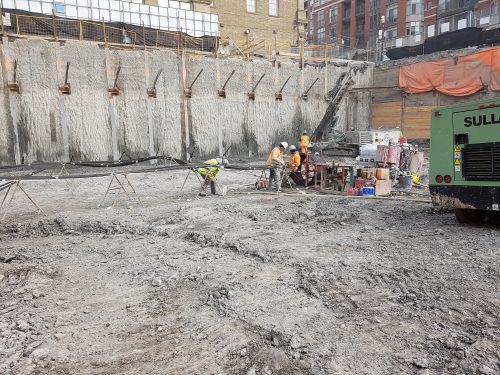 Exterior view of St. Lawrence Market showing construction workers and concrete walls.