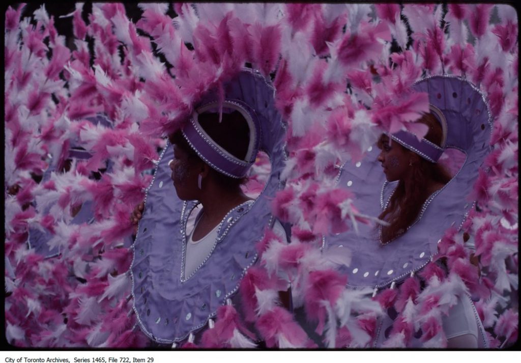 Two women in wearing costumes made of pink feathers fro Caribana carnival