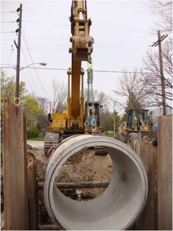 Heavy machinery putting in a newer sewer into the ground