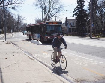 Photo of a cyclist riding in a separated bike lane with pre-cast concrete barriers with reflectors