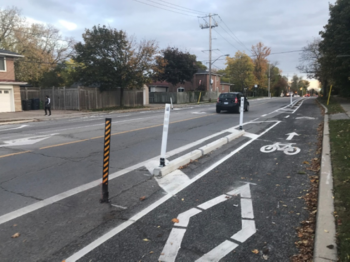 Photo showing separated bike lane with pre-cast concrete curbs and flexible posts