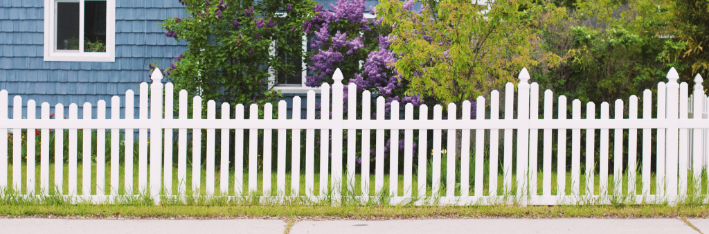 White fence in front of a blue house