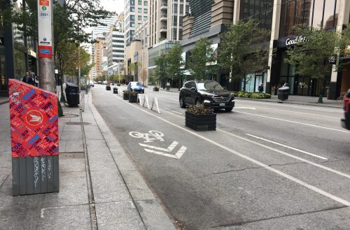 Image of Bloor Street after the bike lane installation with painted bike lanes separated by planters