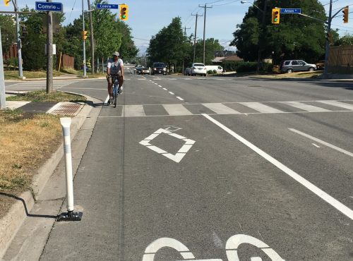 Image of Brimley Road after the bike lane installation with painted bike lanes separated by bollards