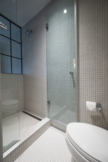 glass shower door in white tile bathroom.