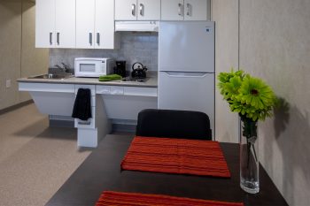 321 Dovercourt Rd. dining table with flowers and view of kitchen fridge and sink. 