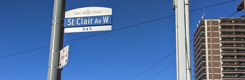 St. Clair Av W street sign against a clear blue sky.