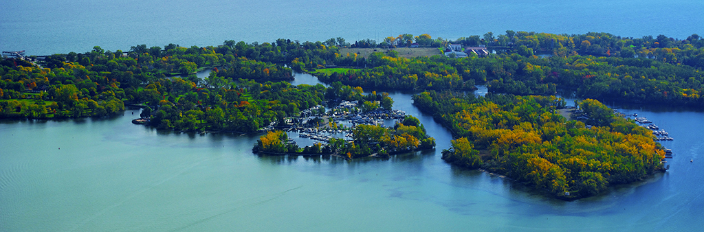 Aerial photograph of Toronto Island in the summer, showing the Toronto Island Marina, green trees and Lake Ontario.