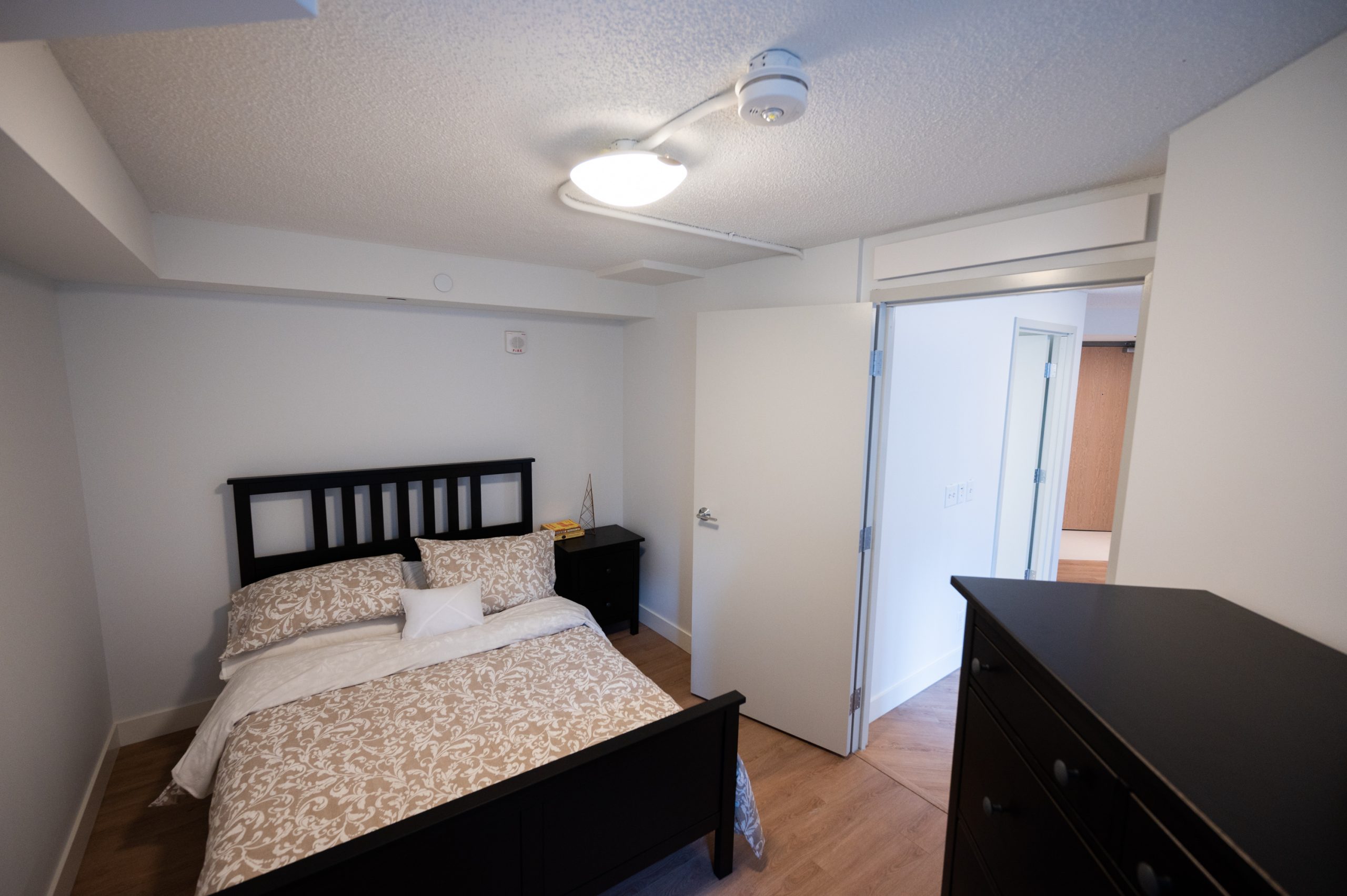 Bedroom with bed, nightstand and dresser in unit of 389 Church St.