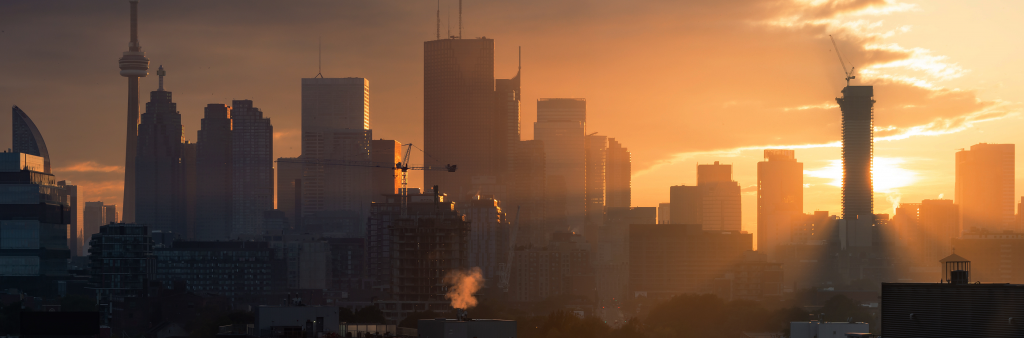 Toronto city skyline at sunset with cranes and construction.