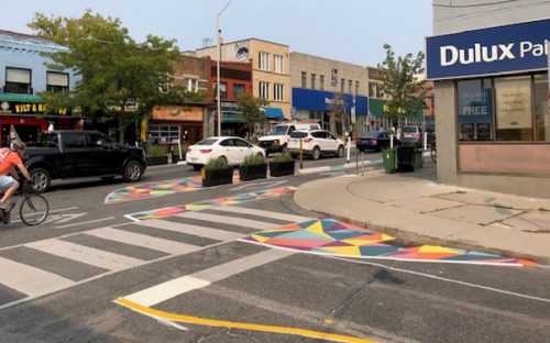 The complete street image shows the use of colourful painted buffers on the street to expand crossing distance for pedestrians. 