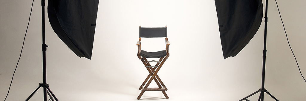 Image depicts director's chair flanked by two shaded photography lights.