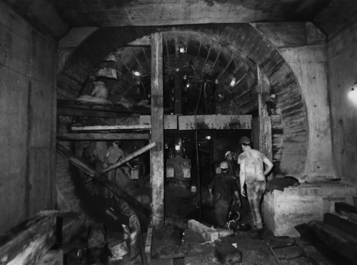 Workers standing in newly constructed subway tunnel.