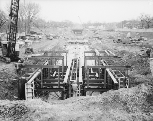 Excavated area with tunnel structural supports being installed. Excavated area runs length of park.