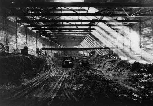 Dump truck and excavator working in the mud of the underground box tunnel area.