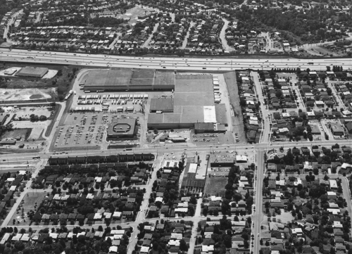 Foreground shows subdivision. Middle of the picture shows an industrial building. Background shows highway and subdivisions.