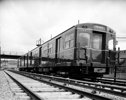 A shiny subway car sits on the tracks.