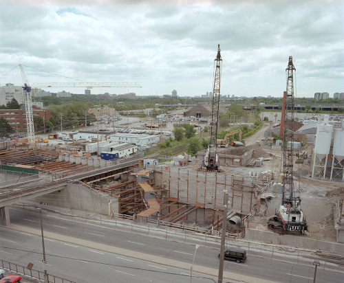 Heavy machinery and work site trailers in background.