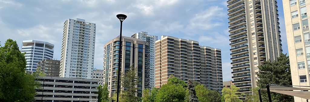 Several mid to high-rise apartment buildings in the Yonge-St Clair neighbourhood with trees and partly cloudy skies