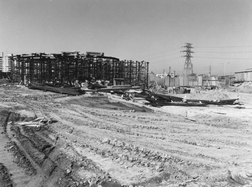 Excavated area for driveway in foreground. Erected steel structure in background.