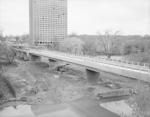 Completion of construction of trackbed on bridge. Background shows trees and construction of tall building.