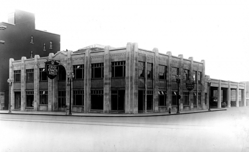 Exterior of a two-storey white stone building with large square windows.