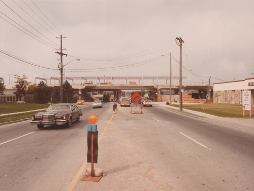 View taken on road with cars looking towards station structure.