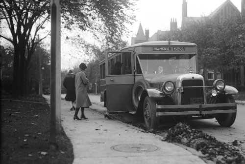 Woman boarding bus from sidewalk.