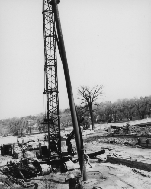 Man standing near large operating drill and heavy machinery.