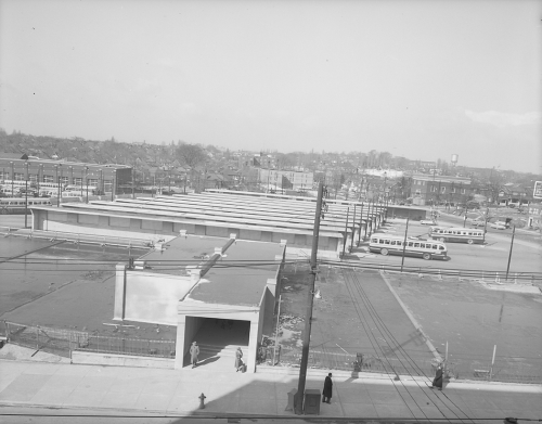 A blocky concrete tunnel with buses in the background.