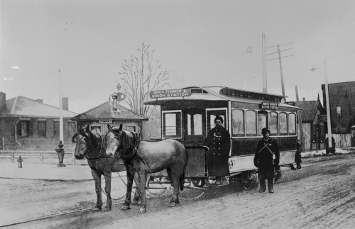 Two horses pulling a small streetcar. The driver is wearing a large winter coat and is standing on the front step. The sign says "North Toronto and Union Station."