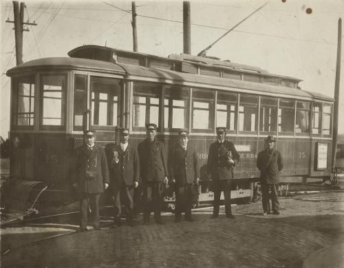 Men in uniforms standing in front of a streetcar.