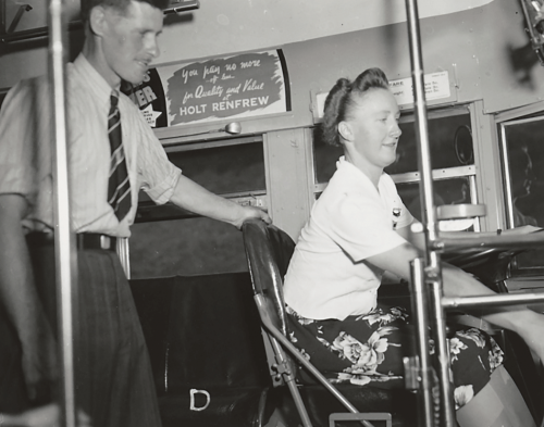 Woman in bus drivers seat with instructor standing behind her