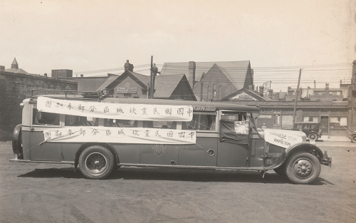 A long bus with banners written in Chinese on the side.