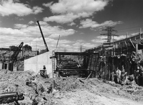 Excavated trench with hoarding and beams installed to secure tunnel structure.