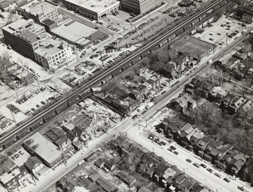 Work site surrounded by houses, parking lots, railroad tracks, and shops