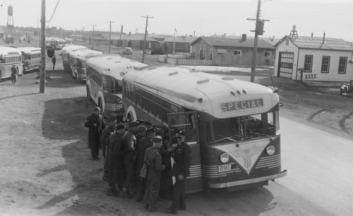 Uniformed men waiting to board lines of buses