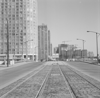 Two sets of newly installed streetcar tracks and sign advertising HLRT. Office towers and condominiums are in the background.