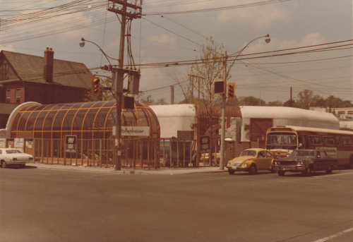 Street corner with glass domed structure, concrete strucutre, cars and TTC bus at lights