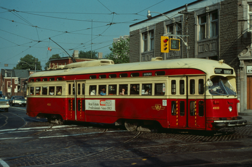 A red and cream coloured streetcar on the road.