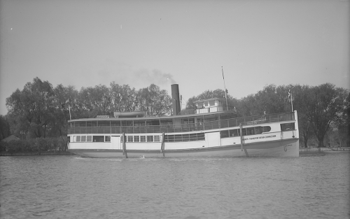 A large wooden ferry with an enclosed lower deck and an open upper deck.