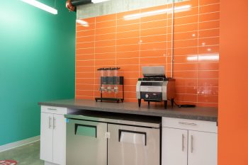 Breakfast area with cereal dispenser and toaster with orange and green walls. 